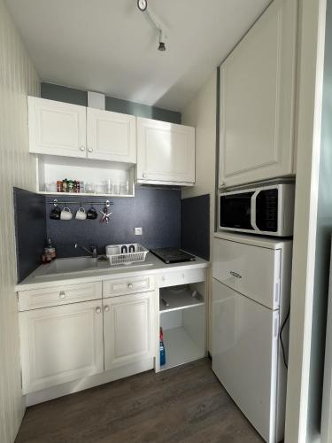 une cuisine avec des armoires blanches, un évier et un micro-ondes dans l'établissement Le Marina, à Saint-Jean-de-Monts