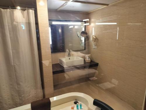 a bathroom with a sink and a mirror and a tub at Shenbaga Hotel And Convention Centre in Puducherry