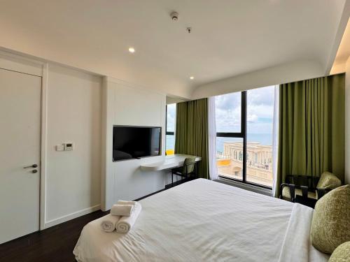 a bedroom with a bed and a desk and a television at Sunset town Phú Quốc in Phu Quoc
