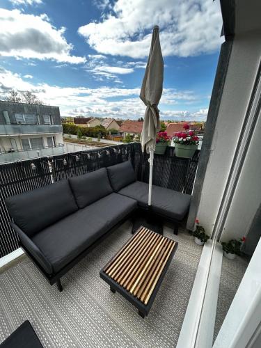 un canapé et un parasol sur un balcon dans l'établissement Superbe nid douillet 42m avec balcon et parking, à Longvic