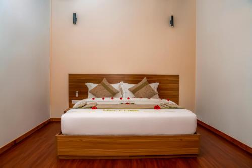 a bedroom with a large white bed with a wooden headboard at Brennia Kottefaru Maldives in Raa Atoll