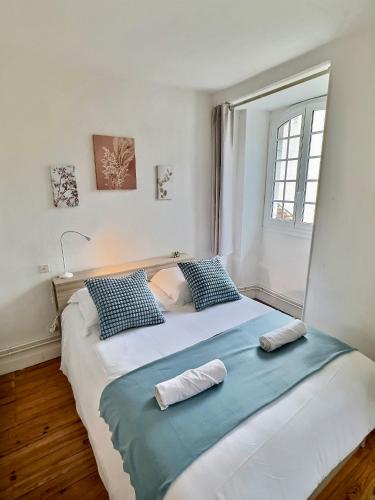 une chambre avec un grand lit avec des oreillers bleus et blancs dans l'établissement WonderHost, une entrée Historique sur la Ville, à Pau