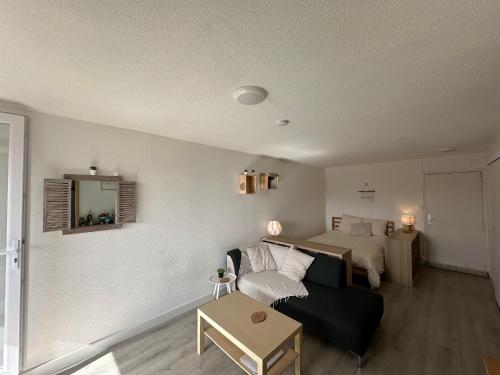 un salon avec un canapé et un lit dans l'établissement cocon les sables d'or, à Marseillan