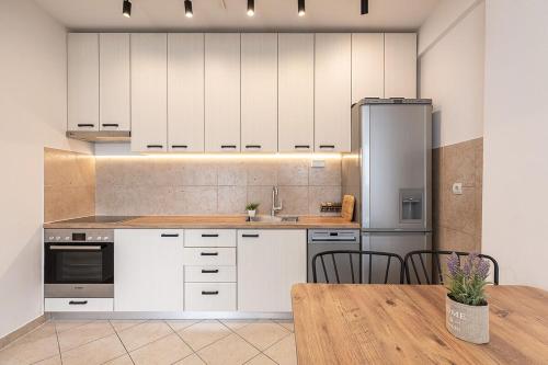 une cuisine avec des armoires blanches et une table en bois dans l'établissement Flat N 5, à Skopje