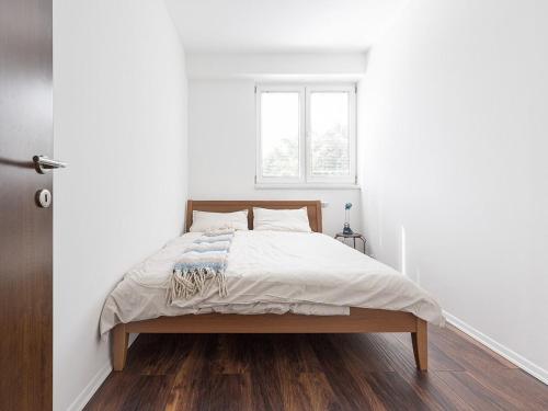 un letto in una stanza bianca con una finestra di Flat N 5 a Skopje