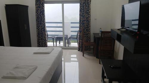 a bedroom with a bed and a television and a balcony at Karickanattu Nature Resort in Idukki