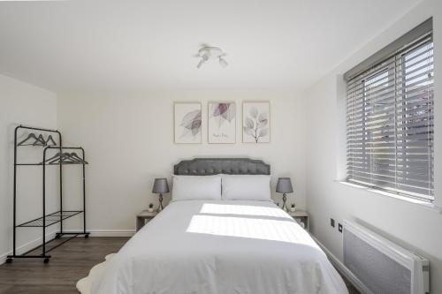 a white bedroom with a bed and a window at Luxurious 2 Bed with Free Parking near Chelmsford City in Chelmsford