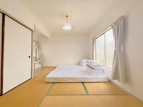 ein weißes Zimmer mit zwei Betten und einem Fenster in der Unterkunft 友縁の家Destined Bonds Haven西巣鴨 in Tokio