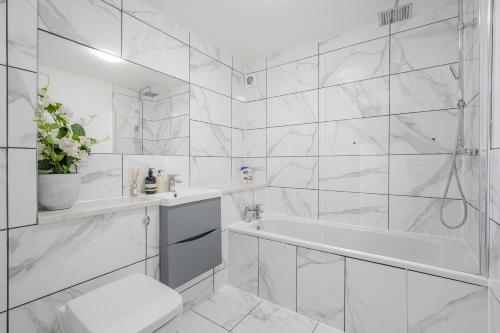 a white bathroom with a tub and a sink at Luxurious 2 Bed with Free Parking near Chelmsford City in Chelmsford