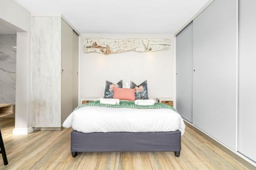 a bedroom with a large bed with white sheets at Zaria Sun Cottage by Host Agents in Gordonʼs Bay