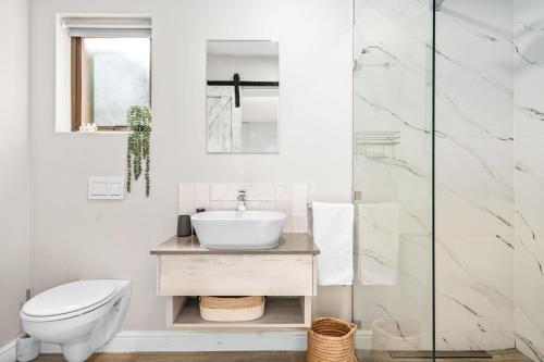 a white bathroom with a sink and a toilet at Zaria Sun Cottage by Host Agents in Gordonʼs Bay