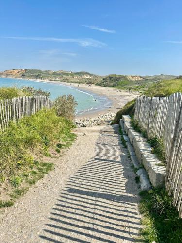 a dirt road next to a fence next to a beach at La Naturelle Duplex 90 in Wimereux