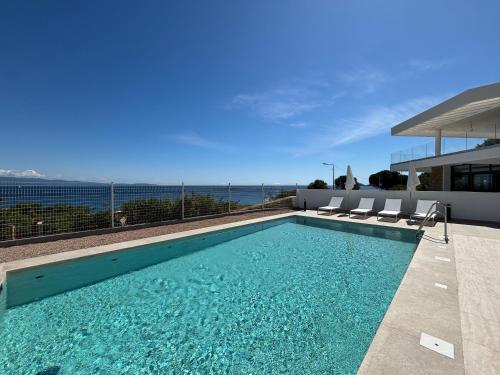 une piscine avec des chaises et l'océan en arrière-plan dans l'établissement Appartement Eden A sanguinaires vue mer avec piscine résidence, à Ajaccio