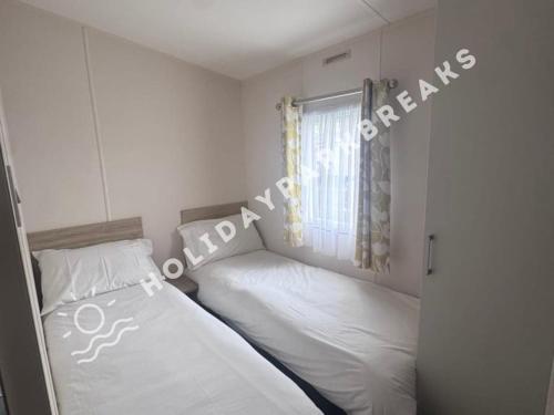 a bedroom with two beds and a window at 3 bedroom Static Home by White Horse, Seal Bay in Selsey