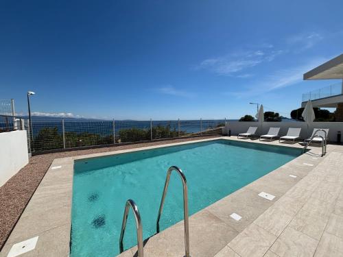 une piscine avec des chaises et l'océan en arrière-plan dans l'établissement Appartement Eden B sanguinaires vue mer avec piscine résidence, à Ajaccio