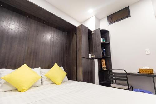 a bedroom with a wooden headboard and a bed with yellow pillows at Brand New Cozy Home in D1 wBalcony in Ho Chi Minh City