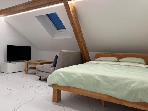 a bedroom with a bed and a tv and a chair at Studio Léo in Bôle