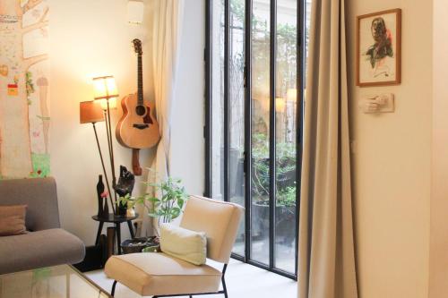 - un salon avec une guitare, une chaise et une fenêtre dans l'établissement Haven of peace with private terrace, à Paris