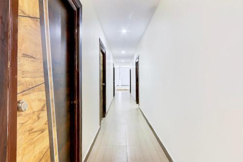 a hallway with white walls and a wooden door at Hotel O Moon Star in Maula Ali