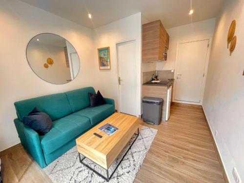 Una sala de estar con un sofá verde y una mesa. en Studio calme et central avec clim, en Niza