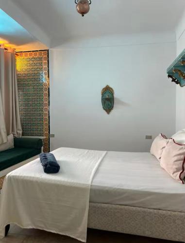 a bedroom with a white bed and a green couch at L'Authenticité in Sidi Bou Saïd