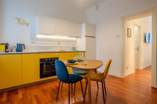 a kitchen with a table and chairs and a kitchen with yellow cabinets at Case Ospitali - Casa La Fontanella, suggestivo bilocale x2 in corte in Cernusco sul Naviglio