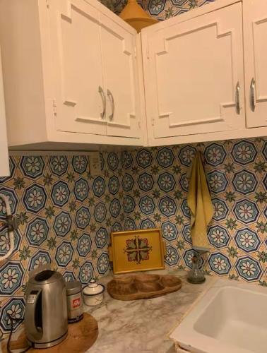 a kitchen with white cabinets and blue and white tiles at L'Authenticité in Sidi Bou Saïd