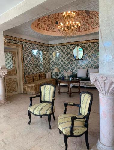 a room with two chairs and a table and a chandelier at L'Authenticité in Sidi Bou Saïd