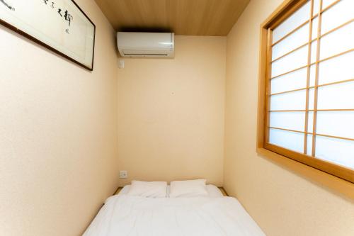 a small room with a bed and a window at Bungetsu Shokaku Kaikan in Kyoto