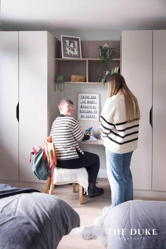 a woman standing next to a man sitting at a desk at The Duke Maynooth in Maynooth