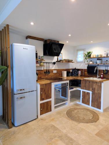 La cuisine est équipée d'un réfrigérateur blanc et de placards en bois. dans l'établissement Évasion au calme - Maison cosy avec piscine et tennis, à Saint-Vallier-de-Thiey