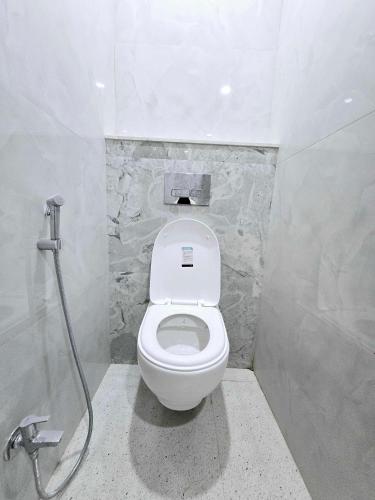 a white toilet in a bathroom with a shower at Vaikuntha Stays Hotel in Indore