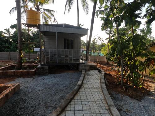 a small house in the middle of a yard at Hallimane Farmstay in Manipala