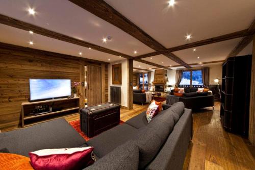 un salon avec un canapé et une télévision à écran plat dans l'établissement Chalet Pleney, à Morzine