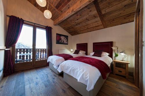 une chambre avec deux lits et une grande fenêtre dans l'établissement Chalet Pleney, à Morzine