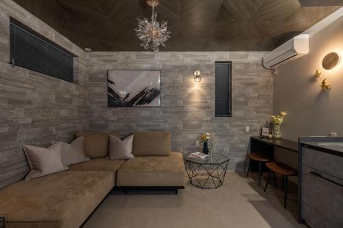 a living room with a couch and a stone wall at JAPAVISTA Luminous in Osaka