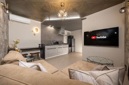 a living room with a couch and a tv on a wall at JAPAVISTA Luminous in Osaka