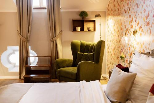 a bedroom with a green chair and a bed at Landgasthof Karner in Frasdorf