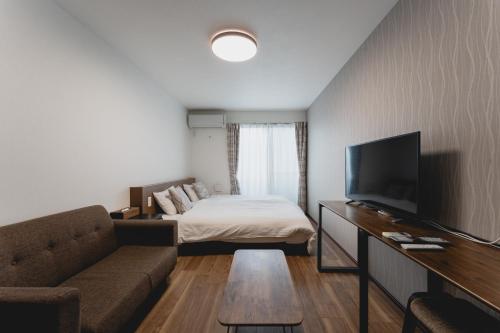 a living room with a couch and a bed and a television at Apartment Hotel KANSO in Kyoto