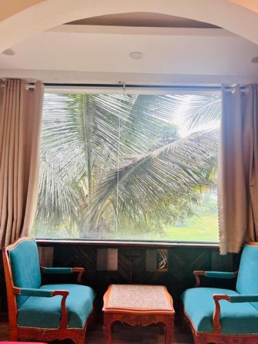 a room with two chairs and a window with a palm tree at Homestay Thác Liên Khương in Ðưc Trọng