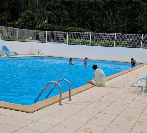 un homme assis dans une piscine avec des gens dans l'eau dans l'établissement Location saisonnière, à Talmont-Saint-Hilaire