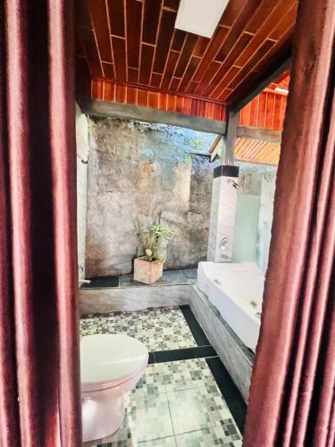 a bathroom with a toilet and a bath tub at Homestay Thác Liên Khương in Ðưc Trọng