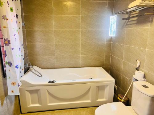 a bathroom with a bath tub next to a toilet at Homestay Thác Liên Khương in Ðưc Trọng