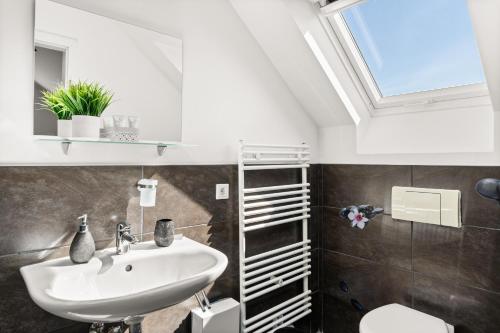 a bathroom with a sink and a toilet and a skylight at MOLA Apartments-Charmante Ferienwohnung im Herdecke Zentrum für 3 Personen-große Dachterrasse-Grill-Gratis Parken-WLAN in Herdecke