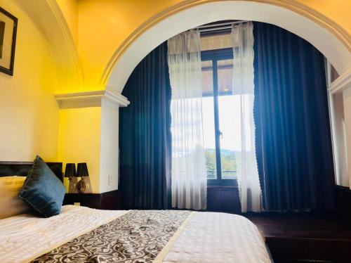 a bedroom with a bed and a window with blue curtains at Homestay Thác Liên Khương in Ðưc Trọng