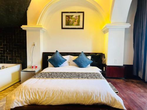 a bedroom with a large bed with blue pillows at Homestay Thác Liên Khương in Ðưc Trọng