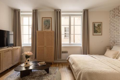 a bedroom with a bed and a tv and windows at Prestigious Main Square Apartment in Kraków