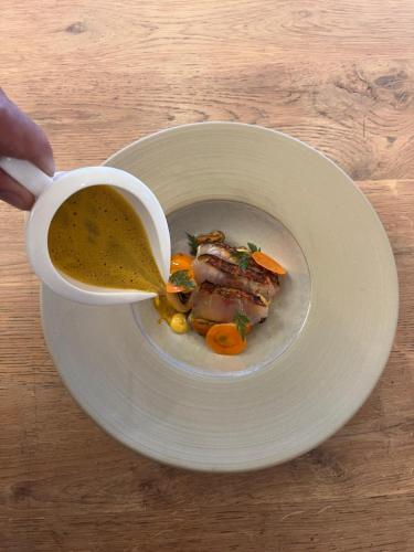 a person is pouring a cup of soup into a bowl of food at Les Roches Brunes in Collioure