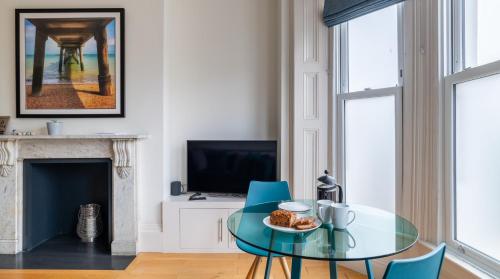 a living room with a glass table and blue chairs at Channel View Apartments in Deal