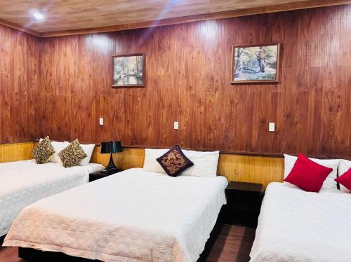 two beds in a room with wooden walls at Homestay Thác Liên Khương in Ðưc Trọng